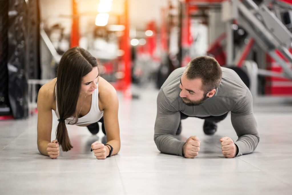 En man och en kvinna utför Plank-övningen, designad för alla muskelgrupper